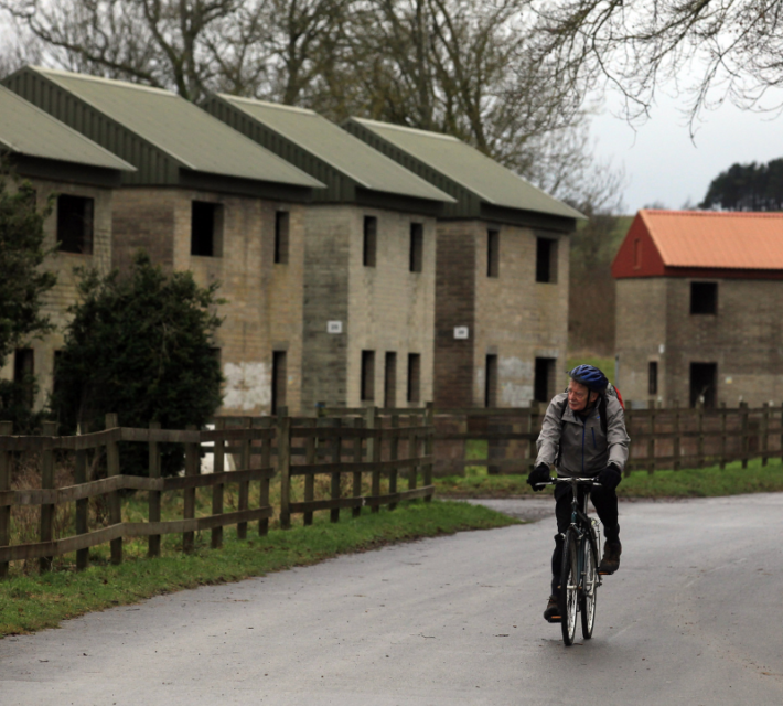 A man cycles past houses, now used for military training as the 10th New Year's Eve peace vigil is held inside the 700-year-old nearby St Giles church in the village of Imber on December 31, 2011 on Salisbury Plain, England.