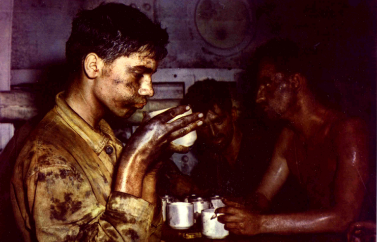 Bedraggled and exhausted US soldiers drink coffee and smoke during combat operations at the Eniwetok Atoll, Marshall Islands, late February 1944.