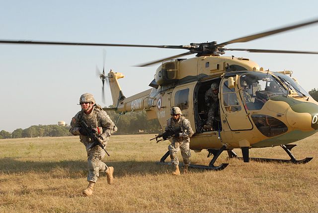 Двое солдат бегут от вертолета армии США