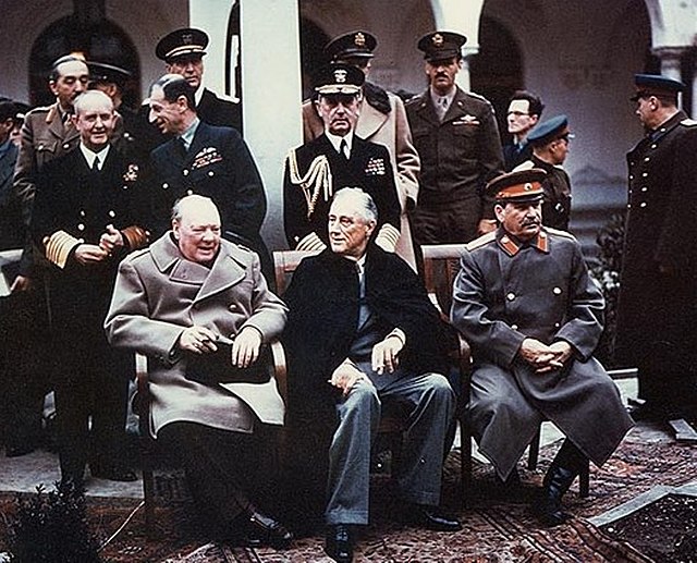 Roosevelt, Stalin and Churchill sitting in front of military men at the Yalta Conference