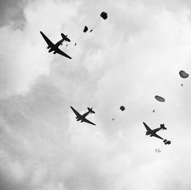 Parachutes floating down from three C-47 Dakotas in the sky