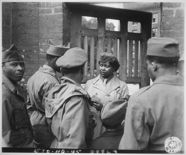 Female soldier surrounded by male servicemen