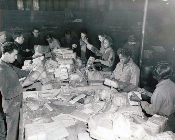 Frenchmen and women of the 6888th Central Postal Battalion sorting mail at a table