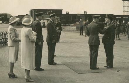 King George awarding Sidney Baker with the Distinguished Service Order while the Royal Family looks on