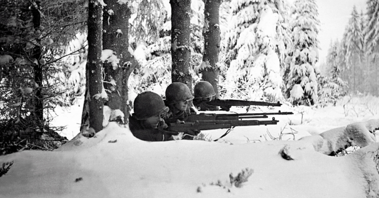 Three US infantrymen aiming their rifles in the snow