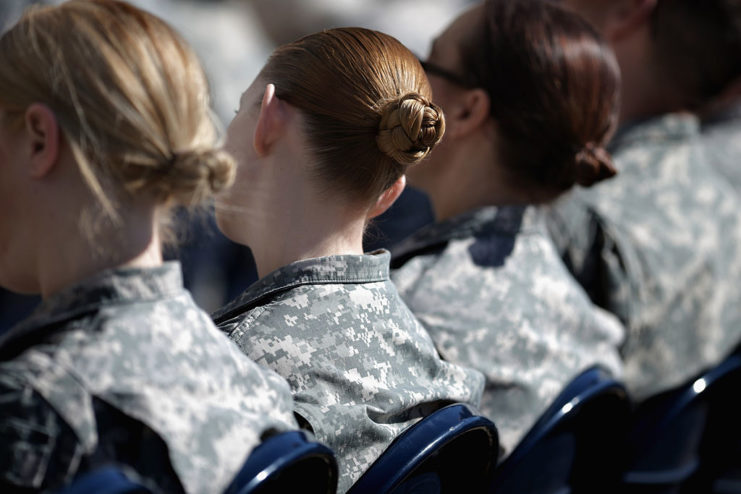 Three female soldiers sitting with their bodies facing away from the camera