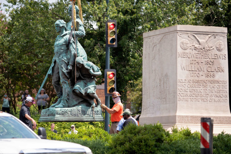 Statue of Lewis and Clark and Sacagawea being hoisted into the air by work crews