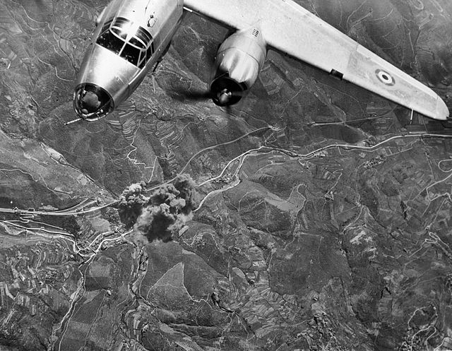 An airplane flying above a recently-bombed area