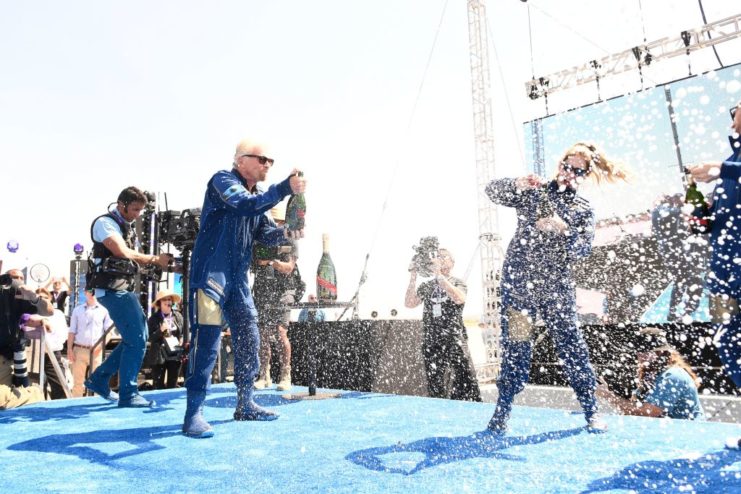 Virgin Galactic crew celebrating on stage with champagne