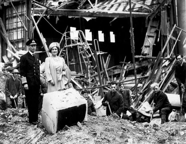 King George VI and Elizabeth the Queen Mother standing in front of a damaged building