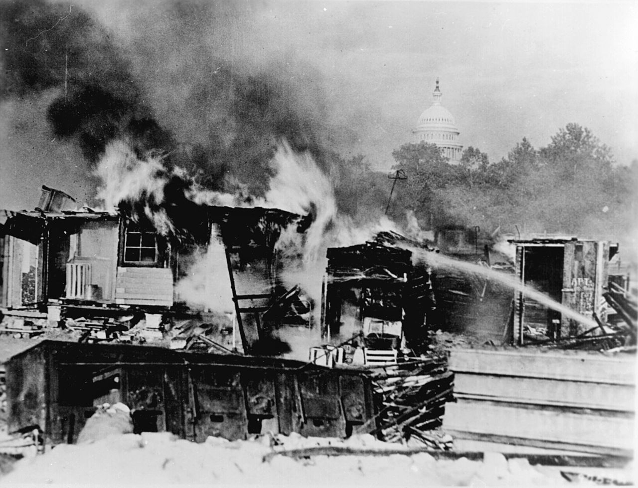 Shacks, put up by the Bonus Army on the Anacostia flats, Washington, D.C., burning after the battle with the military. The Capitol in the background. 1932. (Public Domain)