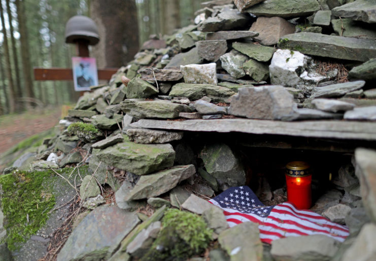 Stone memorial with an American flag and lit candle within