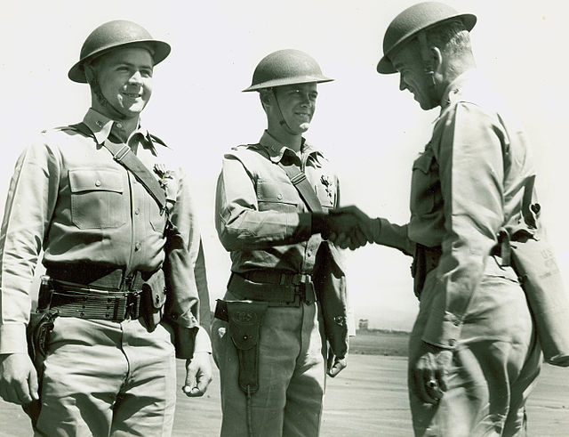 Howard C. Davidson standing before two Army Air Forces officers