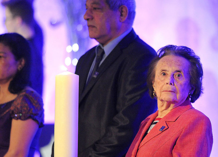 Lily Ebert standing with other individuals in a candle-lit area