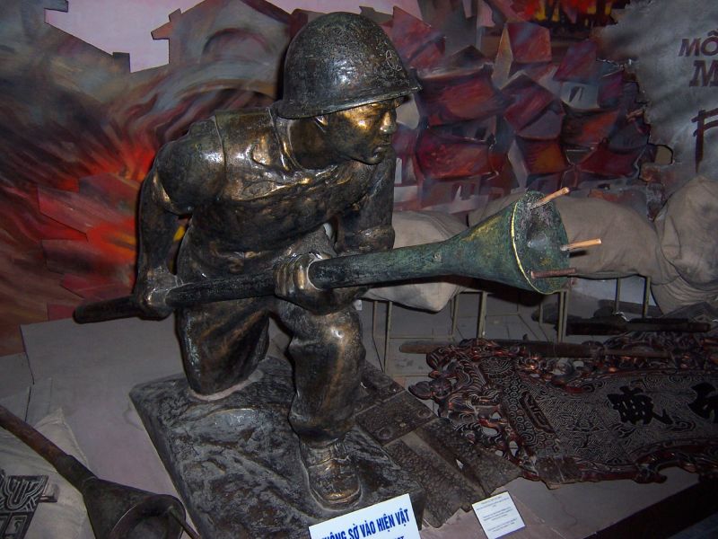 A statue of a Viet Minh soldier holding a Lunge Anti-Tank Mine. Photo taken from the Vietnam Military History Museum, Hanoi, Vietnam. (Photo Credit: Ian Armstrong / Wikipedia)
