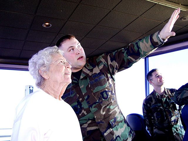Mary Chance VanScyoc with Robert Vojtkofsky in an air traffic control tower, with another airman standing near them