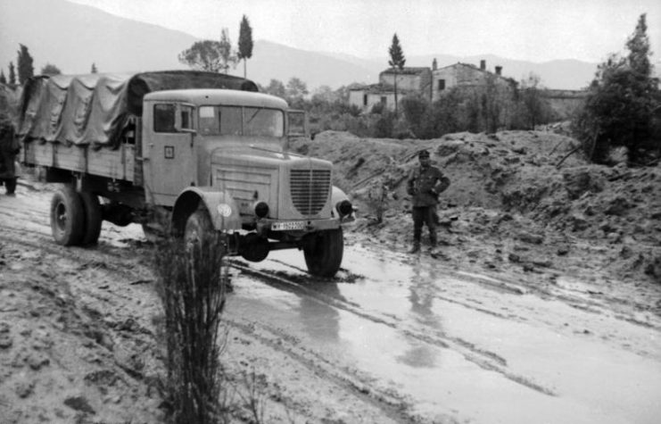 Military truck driving down a muddy road