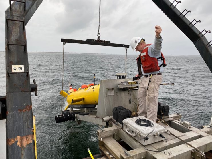 Man lowering an autonomous underwater vehicle into the ocean