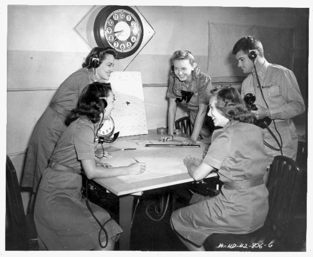 Four members of the Women's Air Raid Defense (WARD) and a male co-worker gathered around a table