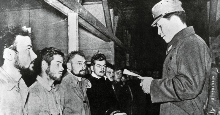 Japanese official standing in front of American prisoners of war (POWs)