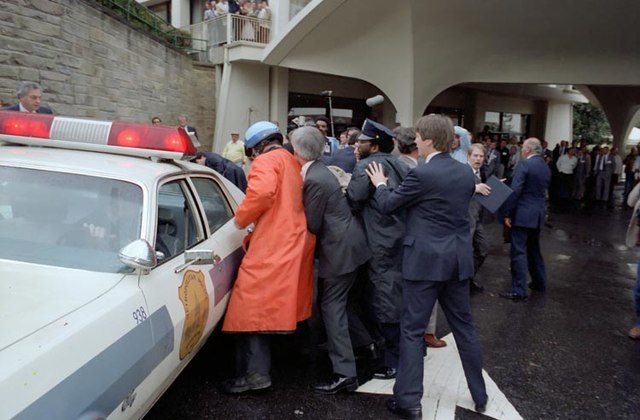 Officers crowd around a police cruisers