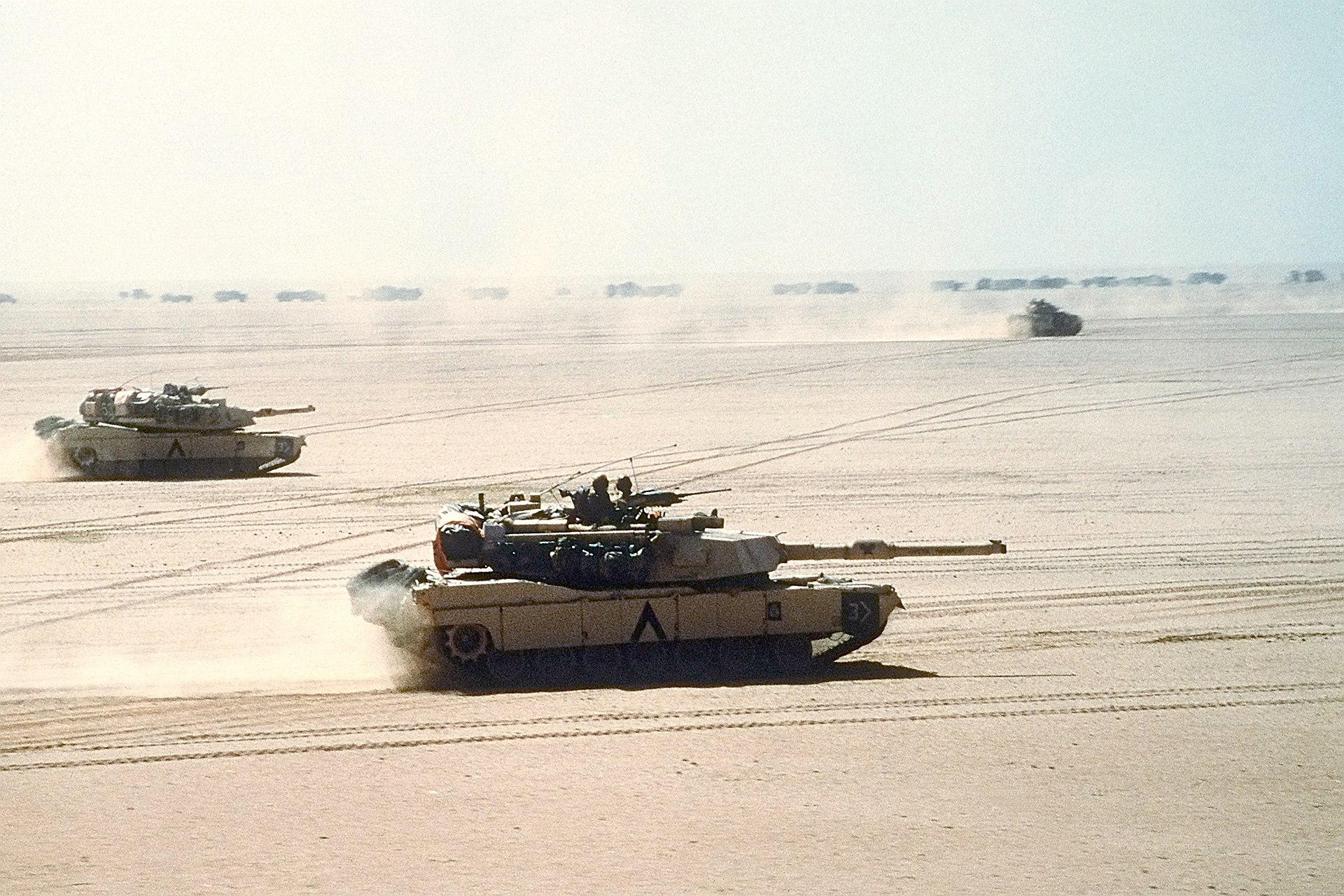 M1A1 Abrams main battle tanks of the 3rd Armored Division move out on a mission during Operation Desert Storm. An M2/M3 Bradley can be seen in background. (Photo Credit: PHC D. W. HOLMES II, US Navy - Still Asset Details for DNST9207834)
