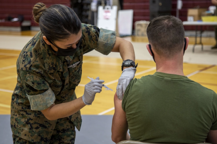 Female soldier giving a male soldier the COVID-19 vaccine