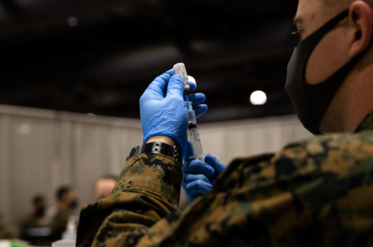 Male soldier filling a needle with the COVID-19 vaccine