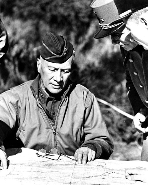 Lloyd Fredendall sitting at a table while looking over documents