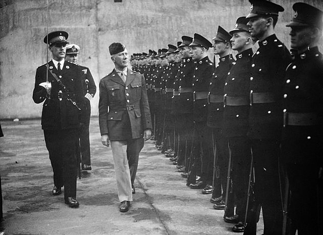 Lloyd Fredendall walking in front of a line of British soldiers