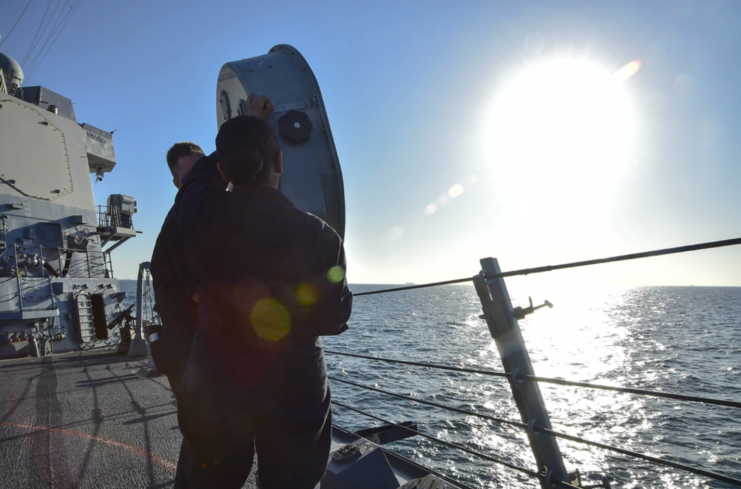 Two Navy personnel standing behind a LRAD