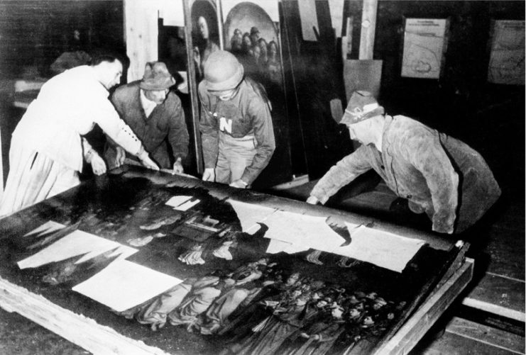 Four men standing over the central panel of the Ghent Altarpiece