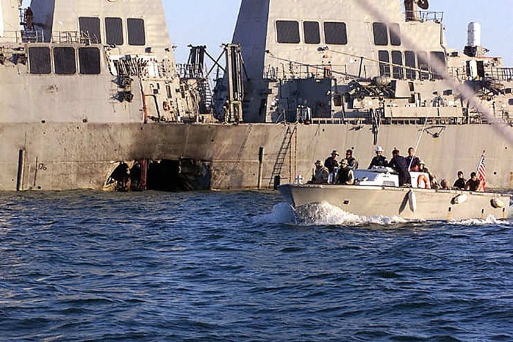 Small boat sailing alongside the damaged USS Cole