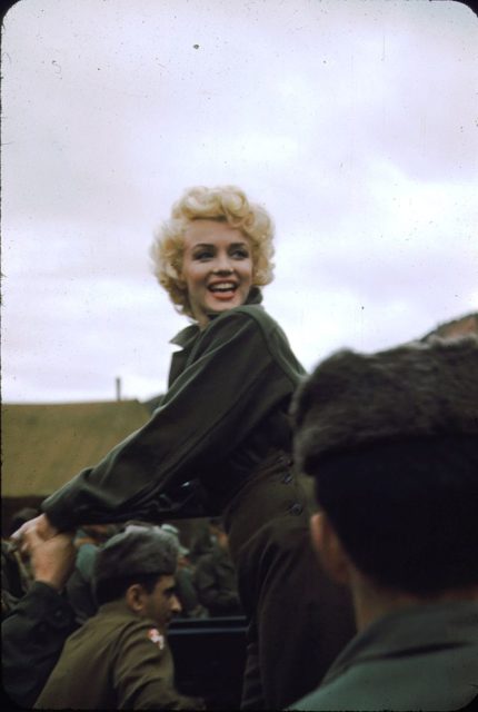 Marilyn Monroe looking behind her while surrounded by troops