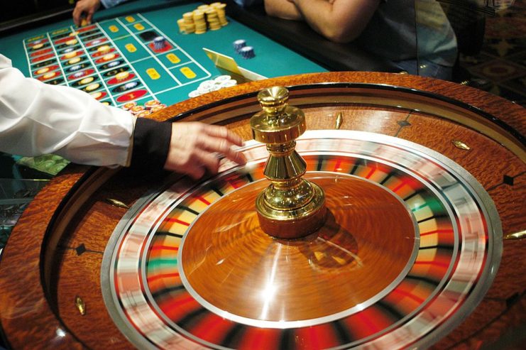 Individual placing a white ball on a spinning blackjack wheel