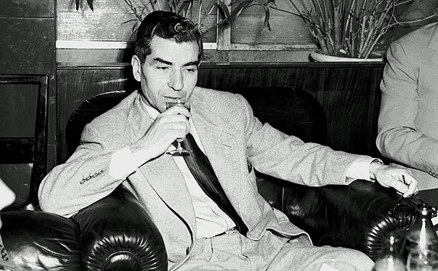 Charles "Lucky" Luciano sitting down and drinking a glass of wine
