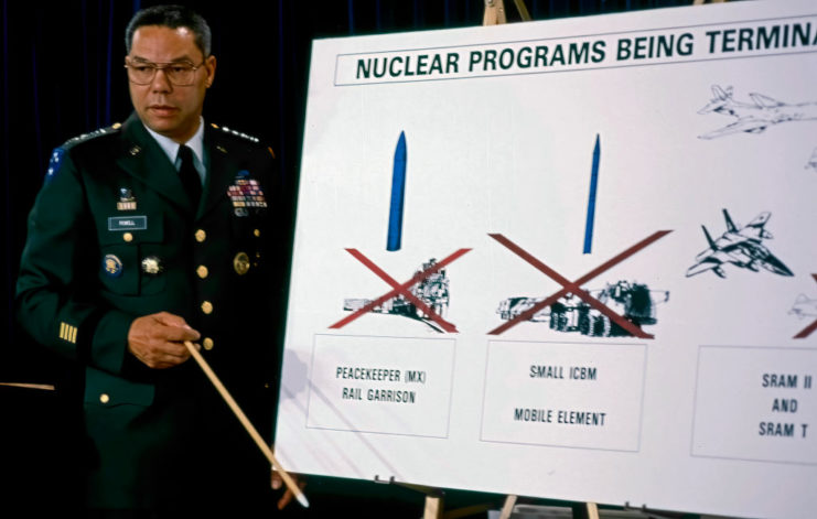 Colin Powell standing beside a presentation on nuclear weapons