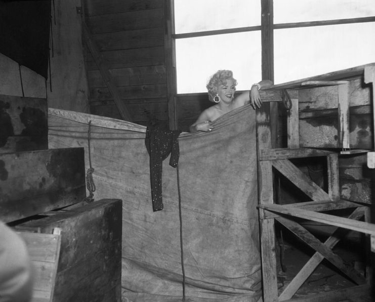 Marilyn Monroe standing behind a large tarp