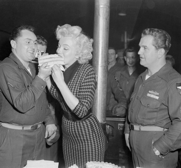 Stanley Closter feeding Marilyn Monroe a piece of cake while other American troops watch on