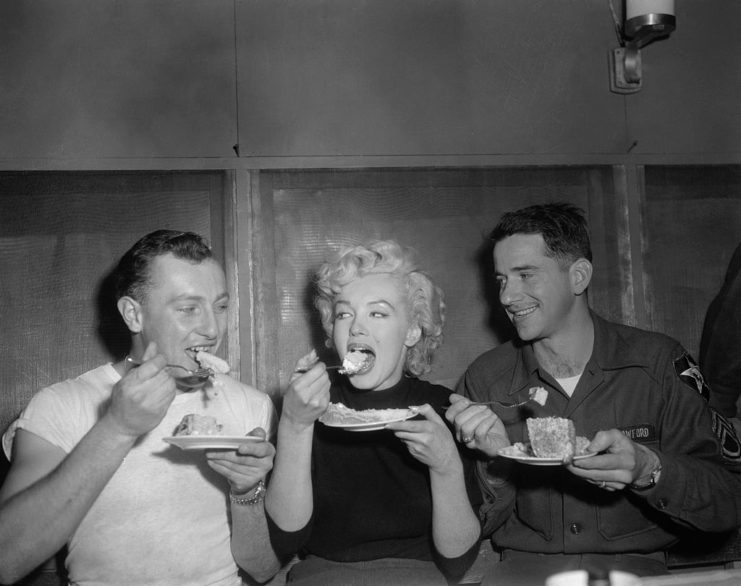 Marilyn Monroe eating cake with Sgt. Gerald Karthauser and Sgt. Harold Crawford