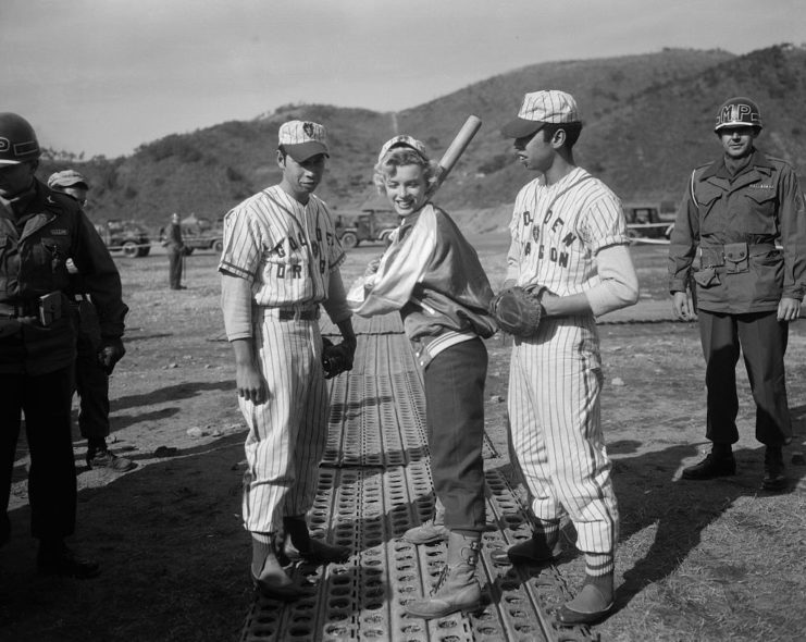 Marilyn Monroe holding a baseball bat while standing between Ernest and Manuel Abril