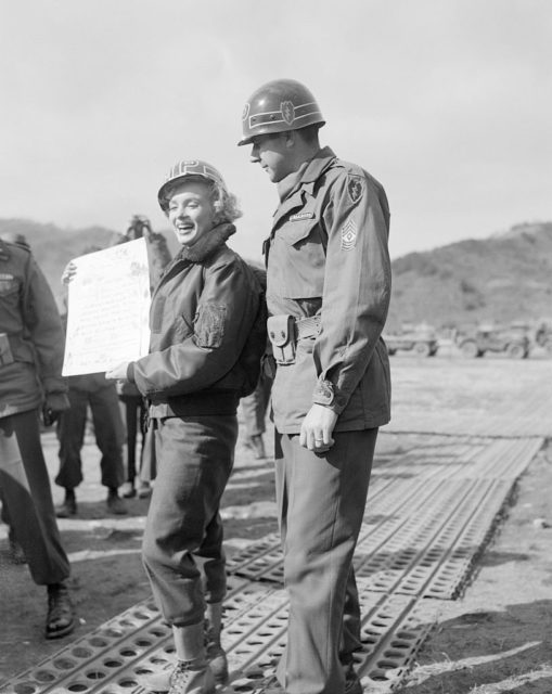 Marilyn Monroe holding up a piece of paper while standing beside Sgt. James C. Callahan