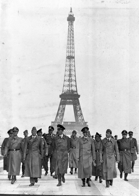 Hitler and other Nazi officials walking in front of the Eiffel Tower