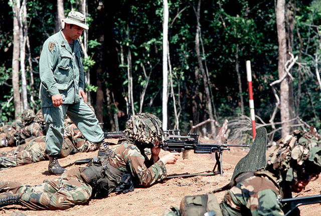 Instructor standing over troops holding rifles