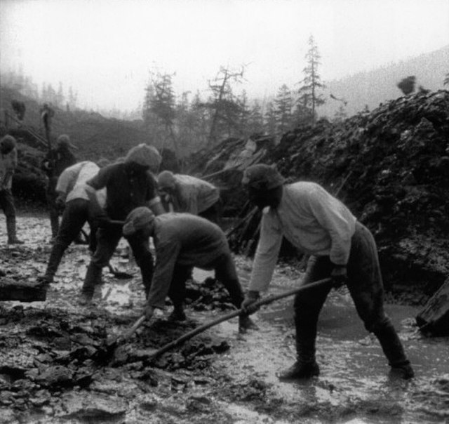 Seven male prisoners working in a muddy area