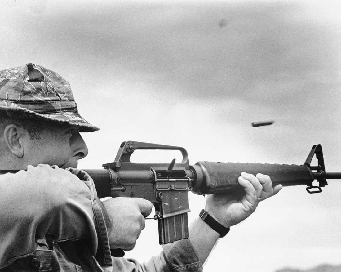 U.S. Navy Boatswain's Mate 2nd Class Lawrence Malone fires M-16 rifle into a known Viet Cong stronghold during a junk patrol in South Vietnam.