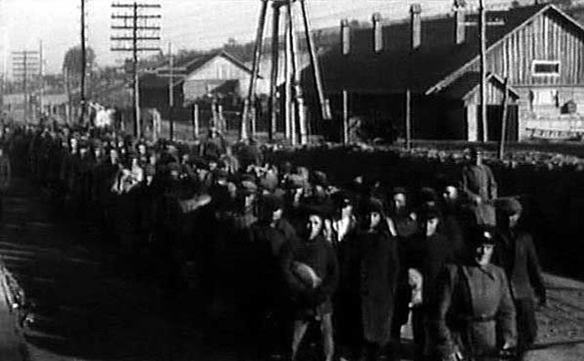 Rows of male prisoners walking within a Gulag