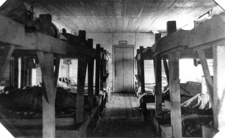 Wooden bunk beds in cramped barracks