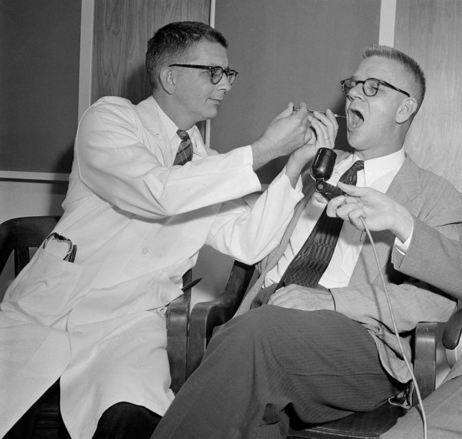 Dr. Harry L. Williams pointing a needle into Dr. Carl Pfeiffer's mouth