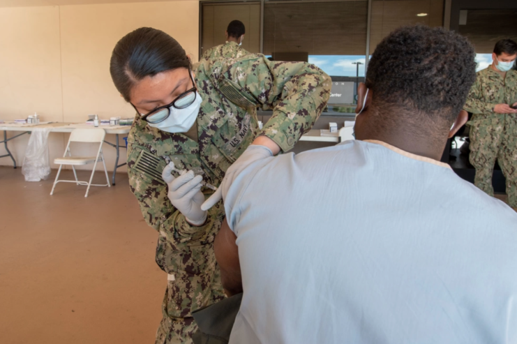 Female sailor giving a male sailor the COVID-19 vaccine